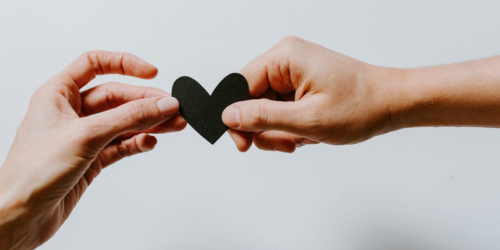 Meta, YouTube, TikTok, and more agree to be graded on mental health impacts | Image shows a black heart being passed from one hand to another