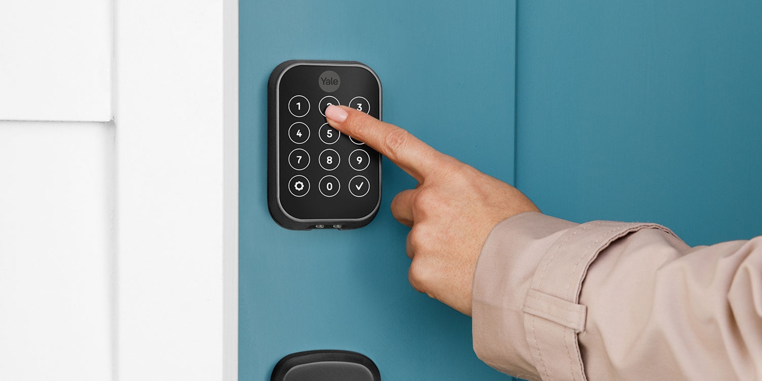 A person pressing a keypad on a door