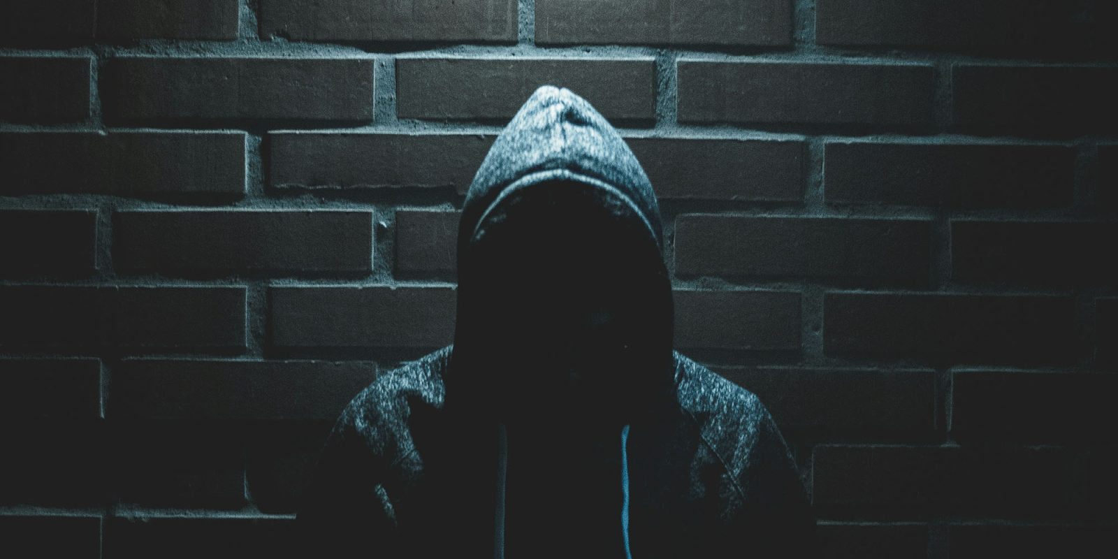 Apple working with British police to tackle iPhone theft | Photo shows a face hidden in darkness by a hoodie