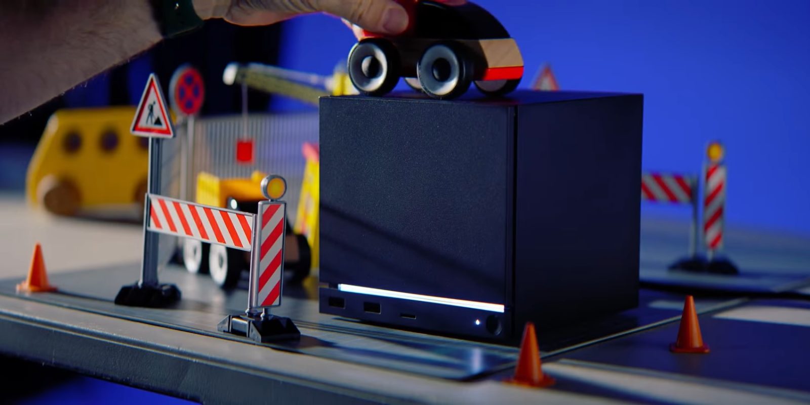 A hand holding a toy car on top of a black box