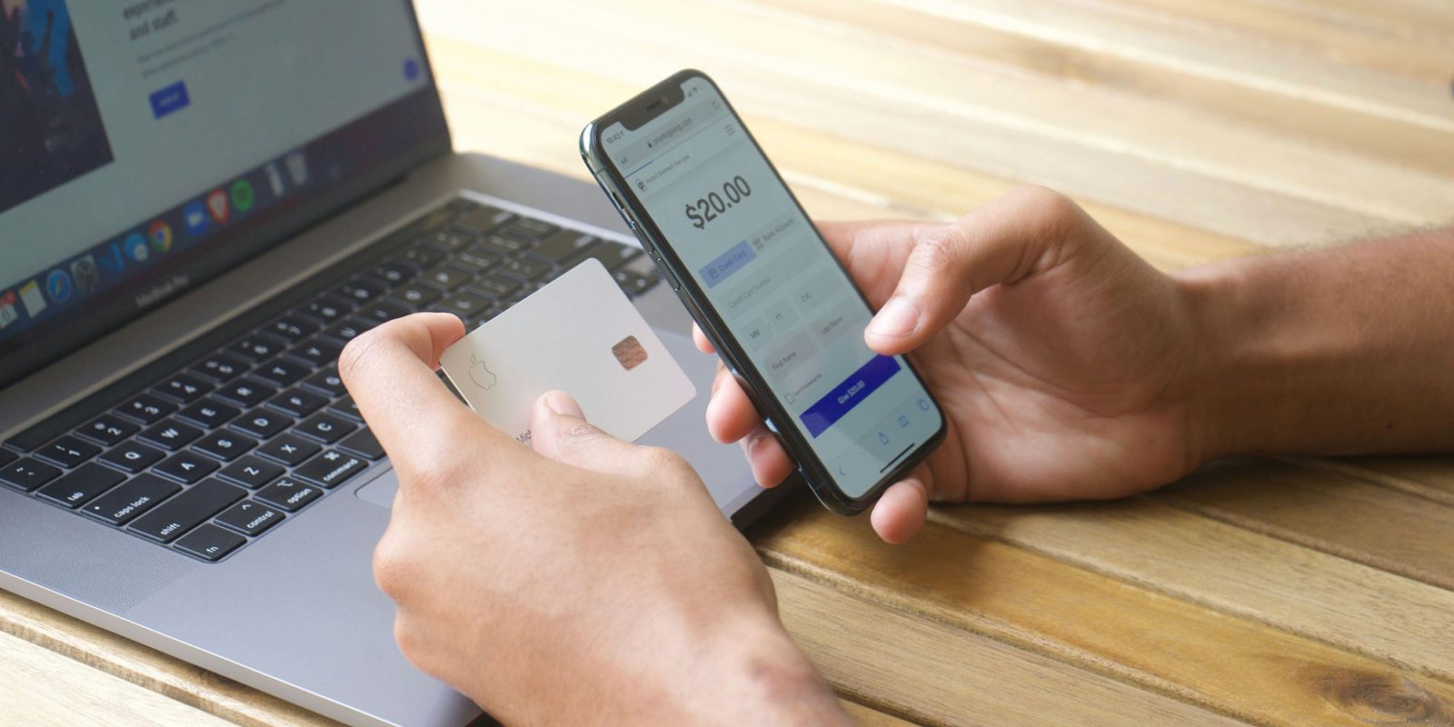 Check your banking app for a potentially important setting | Stock photo shows a man holding an iPhone and an Apple Card in front of him as he looks at a MacBook