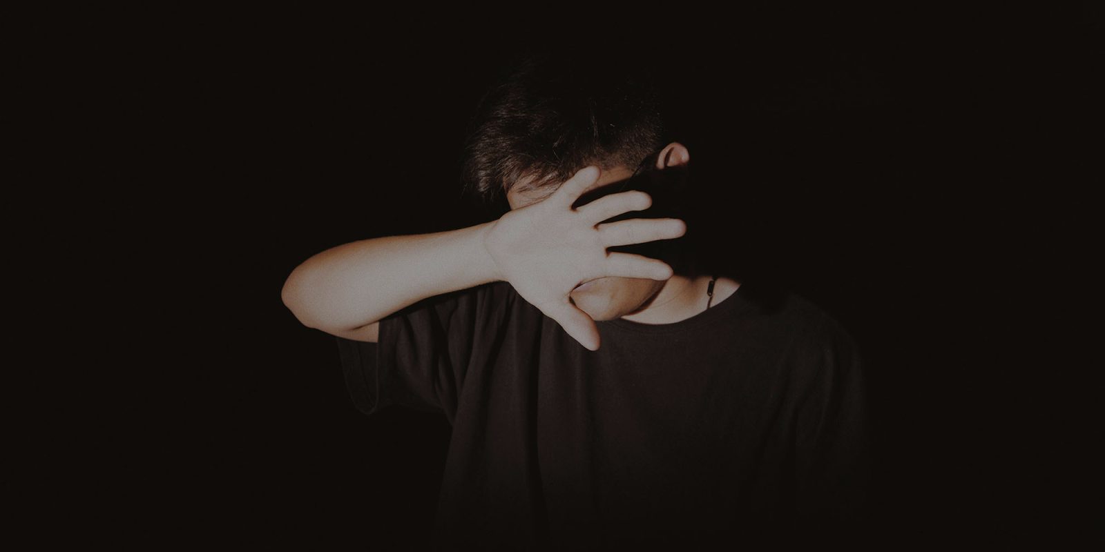 Safety regulator says Apple needs to do more to combat sextortion | Photo shows a teenage boy hiding his face