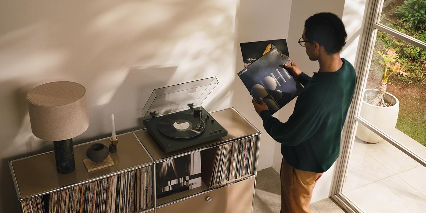 A man holding a record in front of a record player